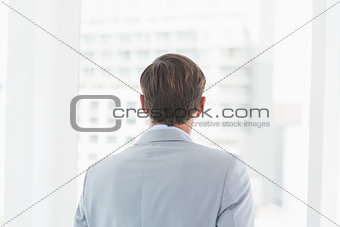 wear view of businessman looking across window