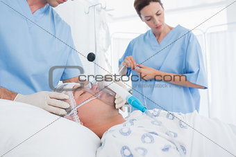 Doctors holding oxygen mask and examining intravenous drip