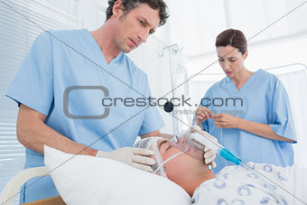 Doctors holding oxygen mask and examining intravenous drip