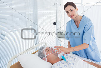Smiling doctor holding patients oxygen mask