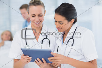 Doctors looking at clipboard while theirs colleagues speaks with patient