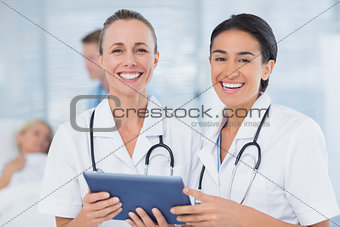 Happy doctors looking at clipboard while theirs colleagues speaks with patient