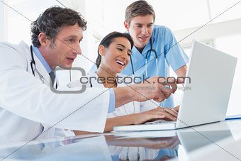 Team of happy doctors working on laptop computer