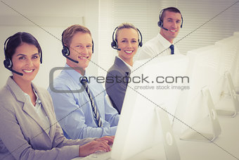 Business team working on computers and wearing headsets