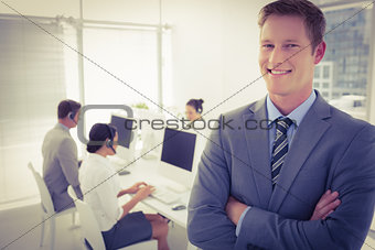 Smiling manager standing arms crossed with staff behind