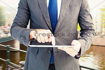 Composite image of businessman using his tablet pc