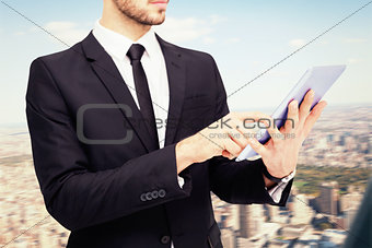 Composite image of mid section of a businessman using digital tablet pc
