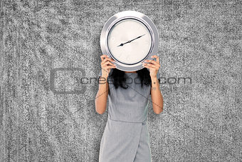 Composite image of businesswoman holding clock