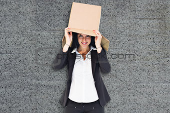 Composite image of businesswoman lifting box off head