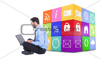 Composite image of businessman sitting on the floor using his laptop