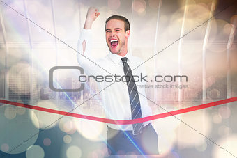 Composite image of businessman crossing the finish line while clenching fist