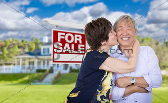 Affectionate Senior Chinese Couple In Front of House and Sign