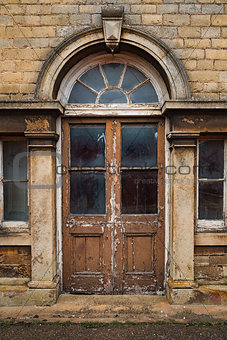 Old decaying wooden double doors in a stone archway