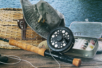 Hat and fly fishing gear on table near the water