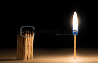Crowd of burnt  matches standing before match on fire concept of