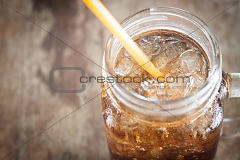 Glass of cola with ice on wooden table