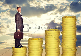 Businessman standing on coins steps