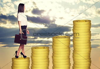 Businesswoman standing on coins steps
