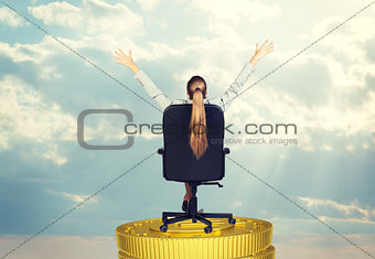 Businesswoman in chair on coins stack, rear view