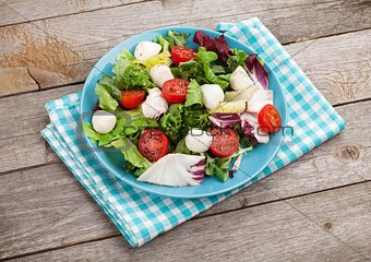 Fresh healthy salad with tomatoes and mozzarella on wooden table