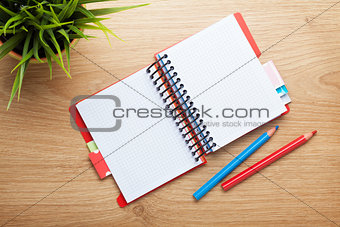 Office table with flower, blank notepad and colorful pencils