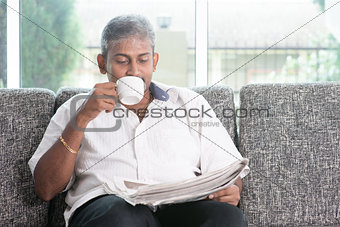 Indian drinking coffee and reading newspaper