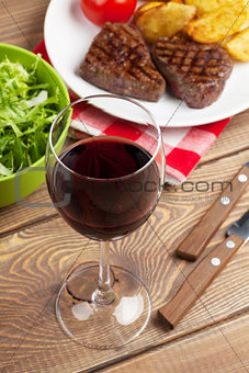 Glass of red wine and steak with salad