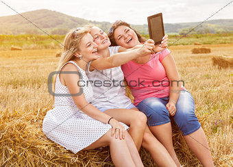 Group of friends in a field taking a picture with a tablet
