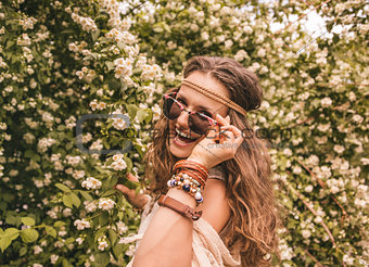 hippie young woman among flowers looking through sunglasses