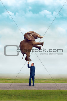businessman holding an elephant with one finger 
