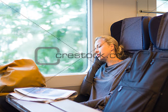 Lady traveling napping on a train.