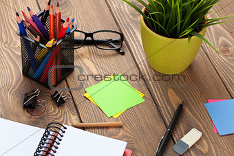 Office table with flower, blank notepad and supplies