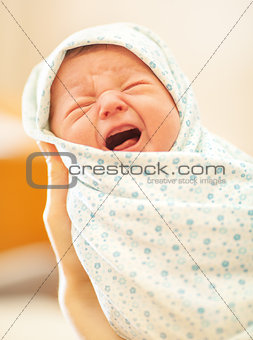 Crying newborn in mothers hands