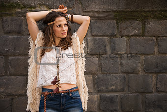 portrait of relaxed boho young woman near stone wall
