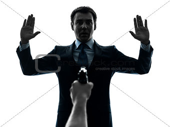 business man arms raised with gun pointing at him  silhouette