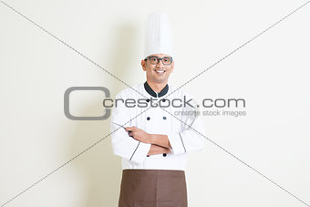 Handsome Indian male chef in uniform with kitchen tools