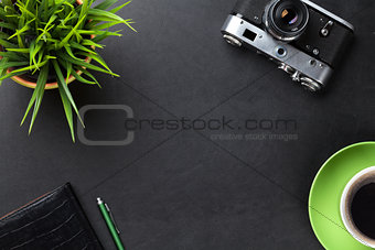 Desk with camera, supplies, coffee cup and flower