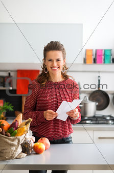 Happy woman with shopping list and bag of fresh produce