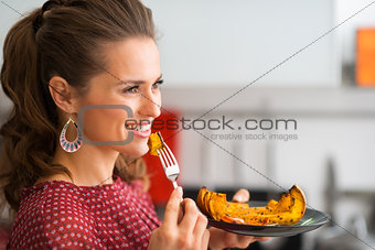 Profile of woman holding bite of roasted pumpkin on a fork