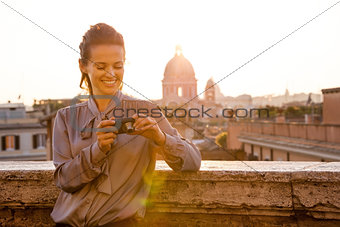 Smiling elegant woman checking photos on camera in Rome