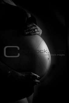Black and white image of a woman's pregnant belly