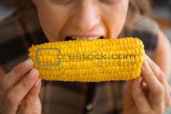 Closeup of woman biting into fresh, crunchy, sweet corncob
