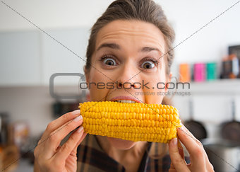 Teasing, happy woman taking big bite of corn on the cob
