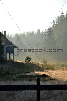 Foggy landscape with cottage in the mountains at the summer morn