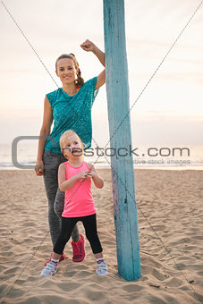 Mother leaning against flagpole standing behind daughter