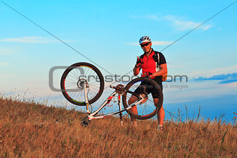 Man cyclist repairing a bike  against blue sky