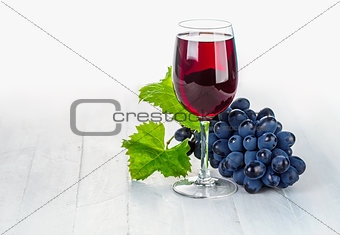 Glass red wine with cluster grapes