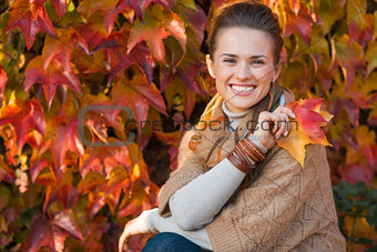 Portrait of relaxed woman with autumn leafs in front of foliage