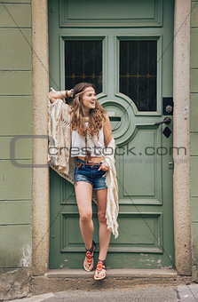Happy hippy-looking woman standing outdoors against wooden door