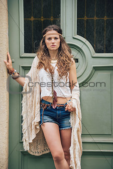 Portrait of hippy-looking woman standing outdoors against door